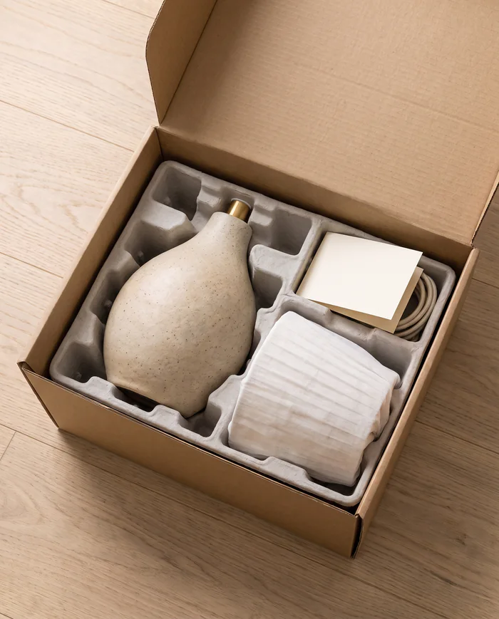 A lamp base and shade packed in moulded paper pulp inside a kraft box