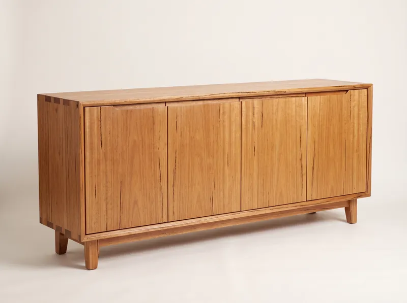 Swan: a long low solid timber sideboard with four flush doors and dovetailed top corners on four short legs