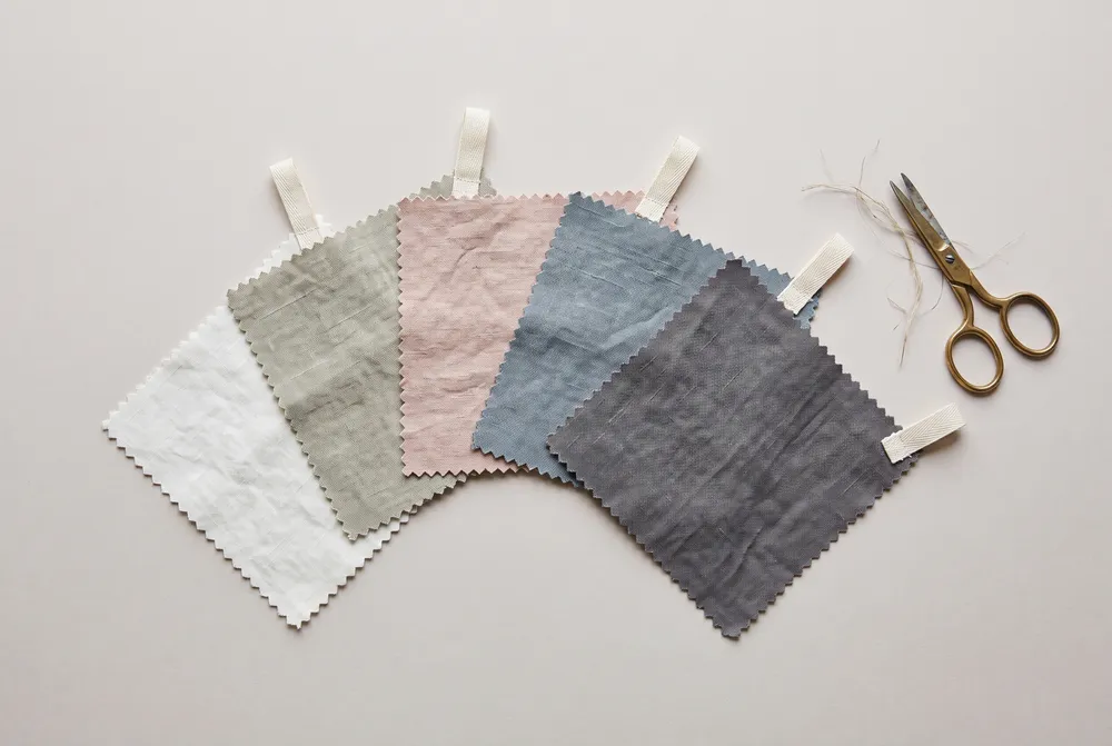 Five linen swatches with pinked edges fanned out on pale paper