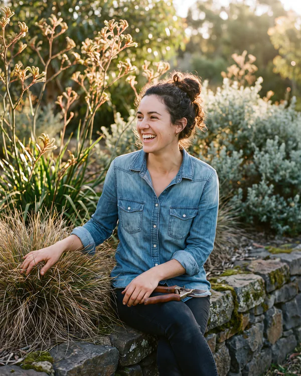 Tess Moreno, horticulturist, sitting on a bluestone wall