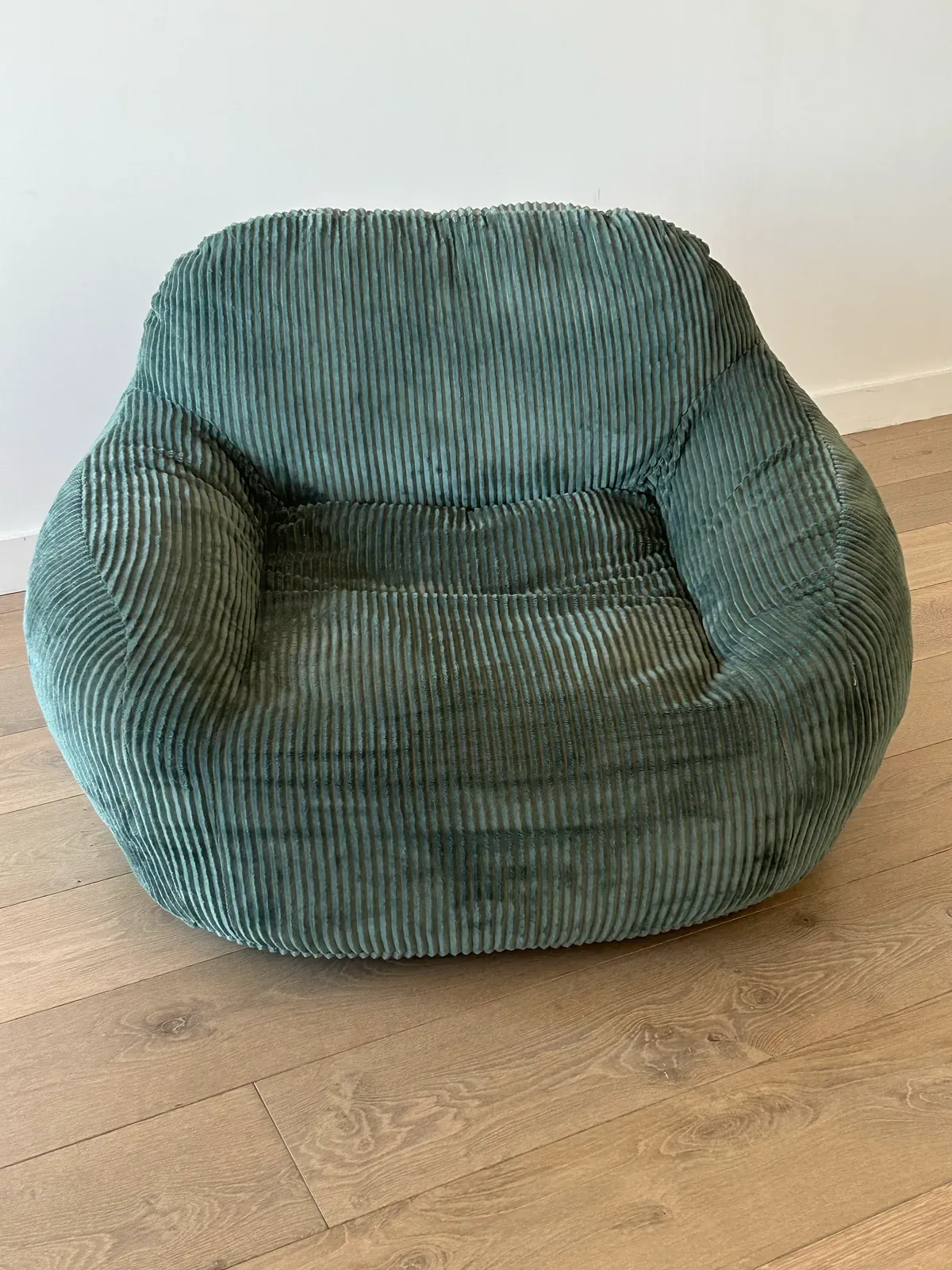 The same armchair photographed on a phone in a bare room.
